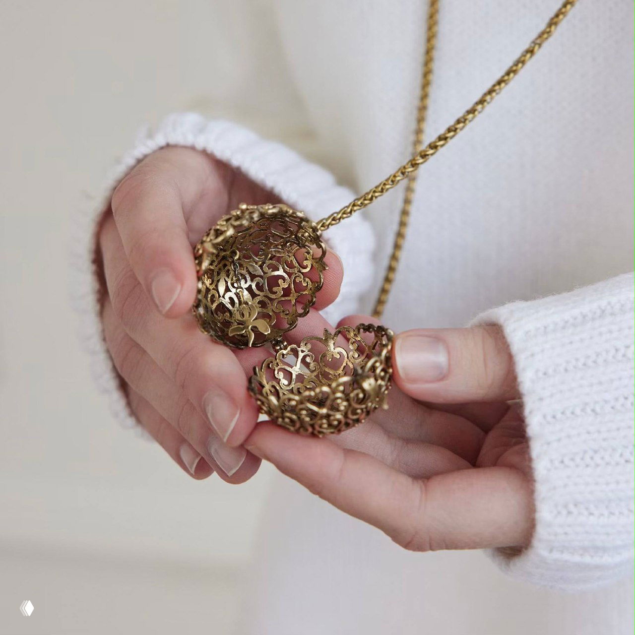 Подвеска SFERA раскрывается в руках модели: показ внутренней конструкции сферы и места для жемчуга, натуральная съемка в светлом интерьере.