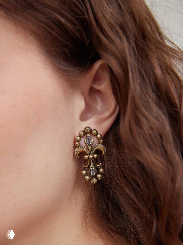 Крупный кадр уха модели с серёжкой IRIS ARALDICO NOVA: видна посадка украшения, мелкие подвески и детализированный орнамент в форме ириса.