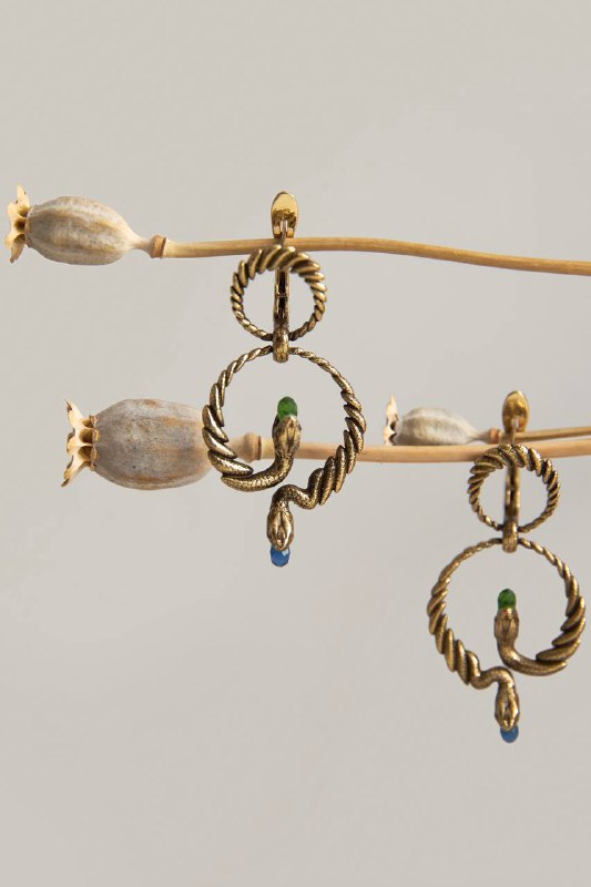 Детальный снимок золотых серег с витой формой и цветными камнями, студийная фотография подчёркивает фактуру и конструкцию украшения