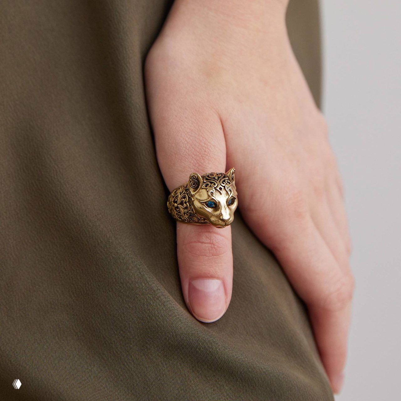 Кольцо Fiore di Firenze на пальце модели — стилизованная голова пумы с инкрустацией голубых камней, тёплый золотистый оттенок металла.