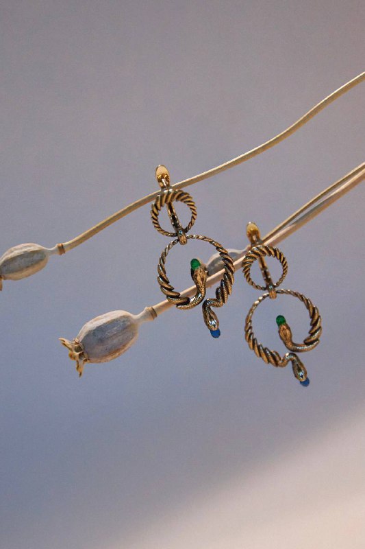 Съёмка серег с подвесками в форме колец и небольшими цветными деталями, композиция на нейтральном фоне подчёркивает форму изделия