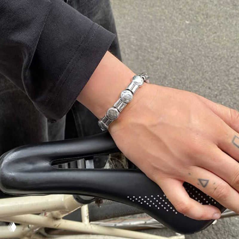 Ещё один кадр браслета Aurea на запястье модели в городской обстановке: вид сбоку, серебристые элементы и повседневный образ