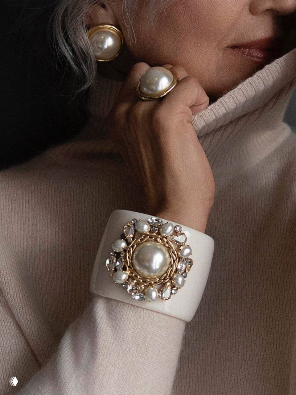 Модель показывает браслет и кольцо с крупными жемчужными вставками Майорика — тёплый осенний образ с приглушённой палитрой и фактурой свитера.