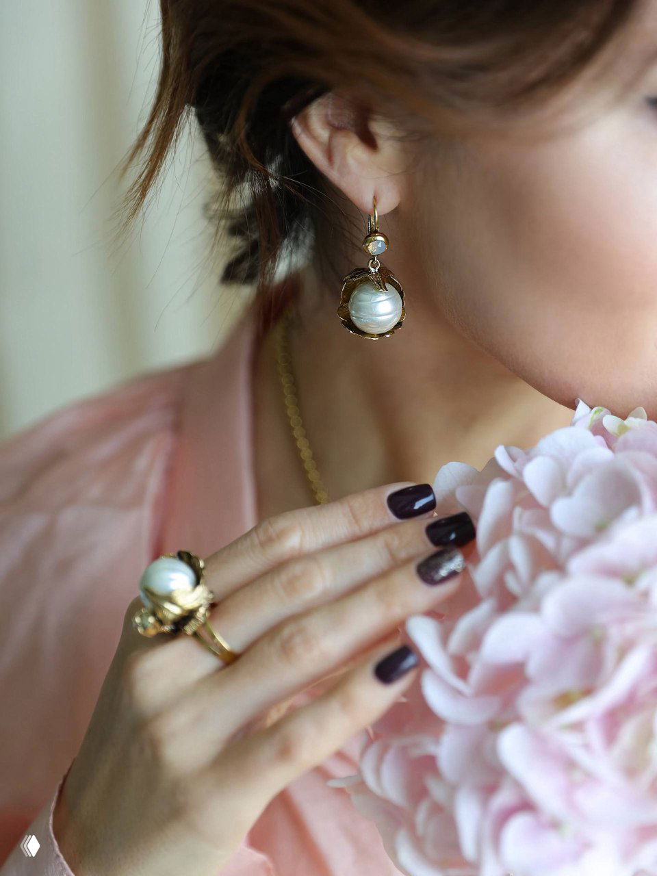 Крупный кадр серьги и кольца с жемчужными вставками Майорика на руке и ухе модели — тонкая позолоченная фурнитура и мягкий свет.