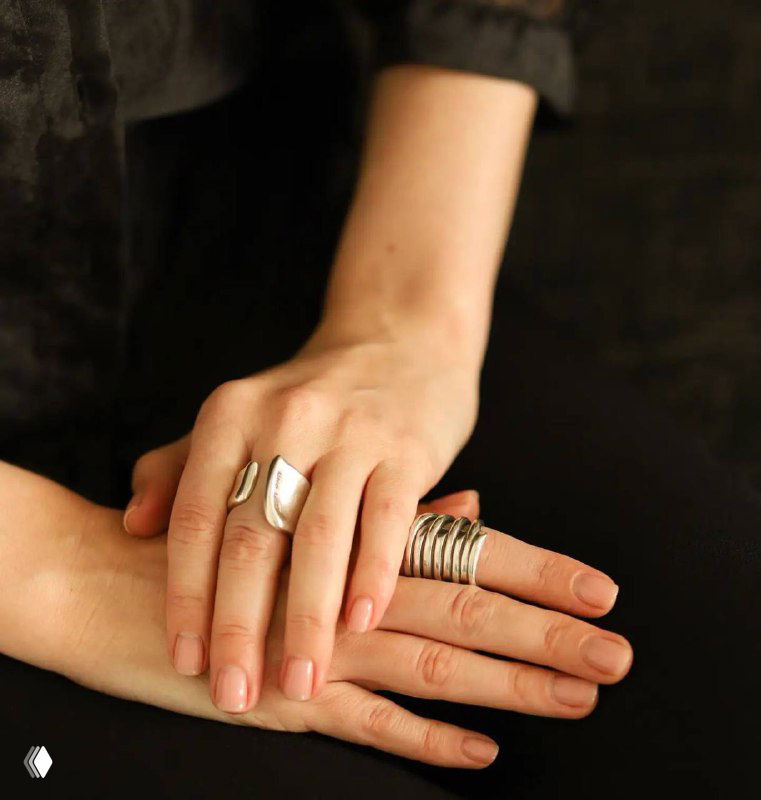 Руки с несколькими кольцами UNOde50 — показ посадки украшений и текстуры металла в тёплой студийной подсветке.