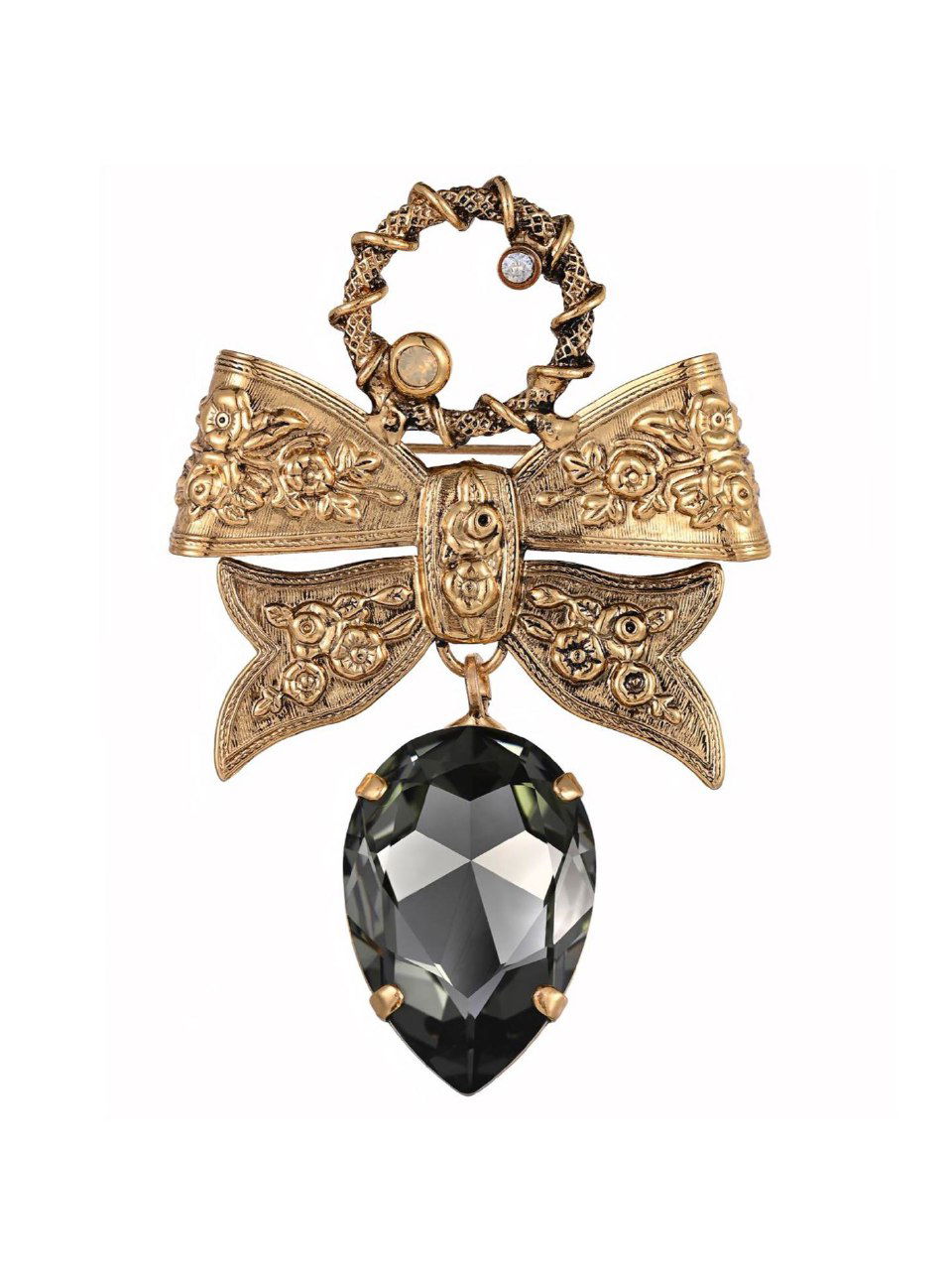 Золотистая брошка в виде банта с крупным темным каплевидным кристаллом на белом фоне, демонстрация декоративной формы