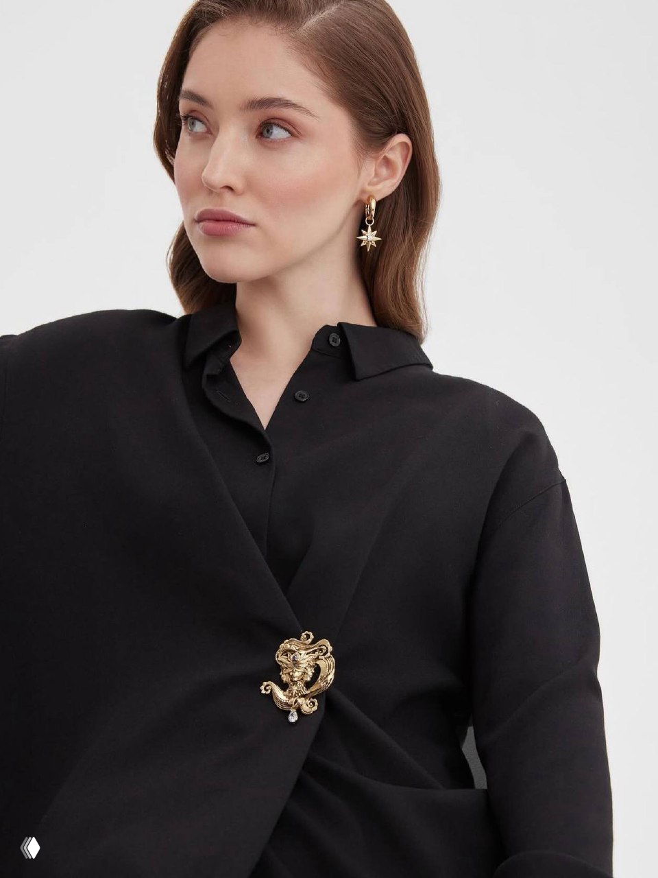 Модель в черной блузе и пиджаке с золотой декоративной брошью, показ расположения украшения на лацкане и рукаве