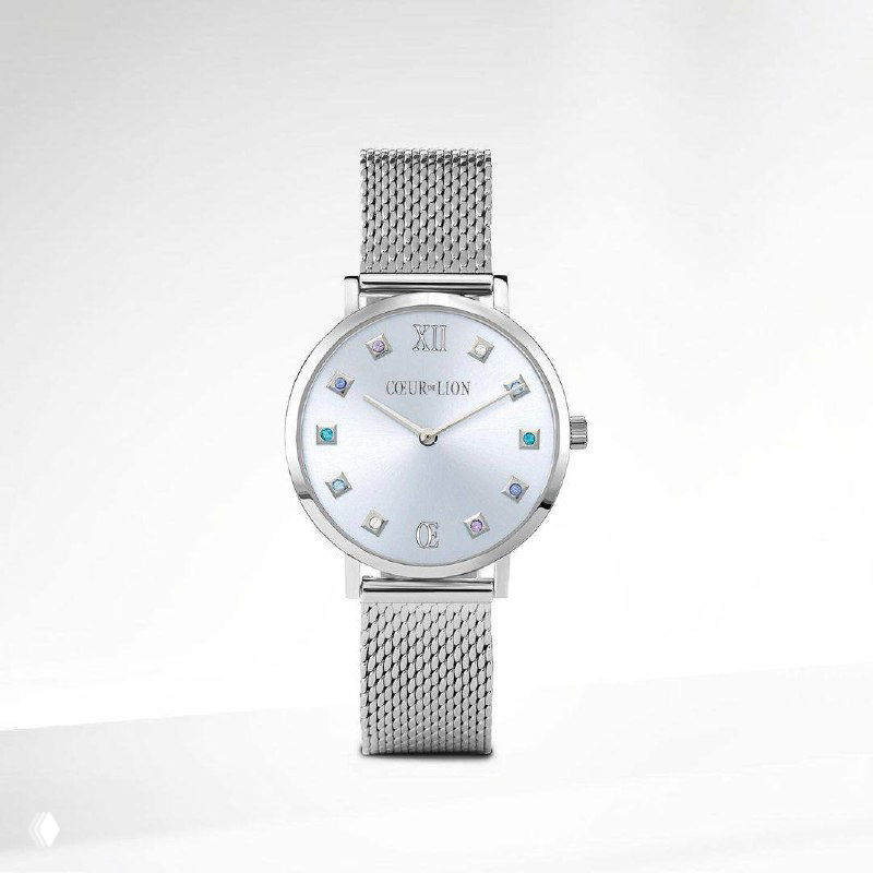 Крупный план круглых серебристых часов Coeur de Lion с нежным циферблатом и вставками кристаллов Swarovski на белом минималистичном фоне.