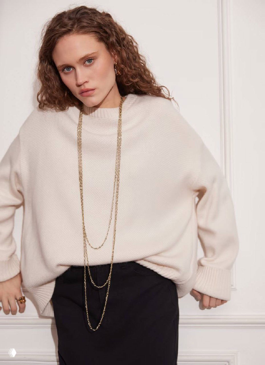 Модель в светлом объёмном свитере носит несколько длинных золотистых цепей Fiore di Firenze, подчёркивая тренд многослойности.