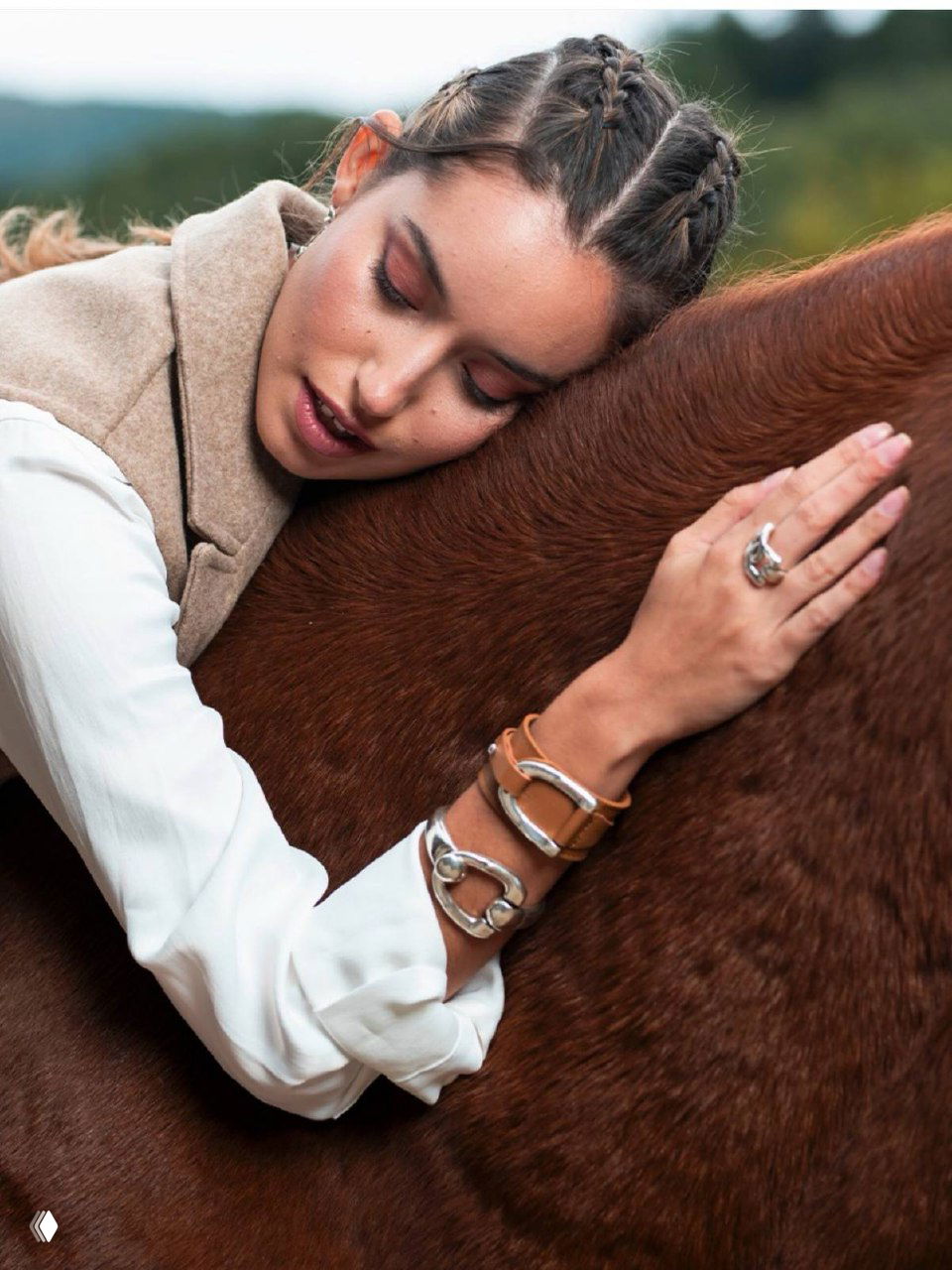 Модель обнимает лошадь, на запястьях кожаные браслеты и серебряные украшения коллекции Equus de Ciclon на фоне природы