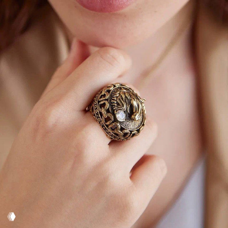 Кольцо из коллекции Fiore di Firenze Cavallo в золотистом тоне с рельефной головой лошади и светящимся камнем, крупный план на руке модели, стильный винтажный дизайн.