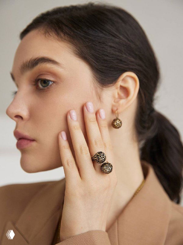 Профиль модели в серьгах и кольце Sferra от Fiore di Firenze: золотистые ажурные украшения на нейтральном фоне, демонстрация образа.