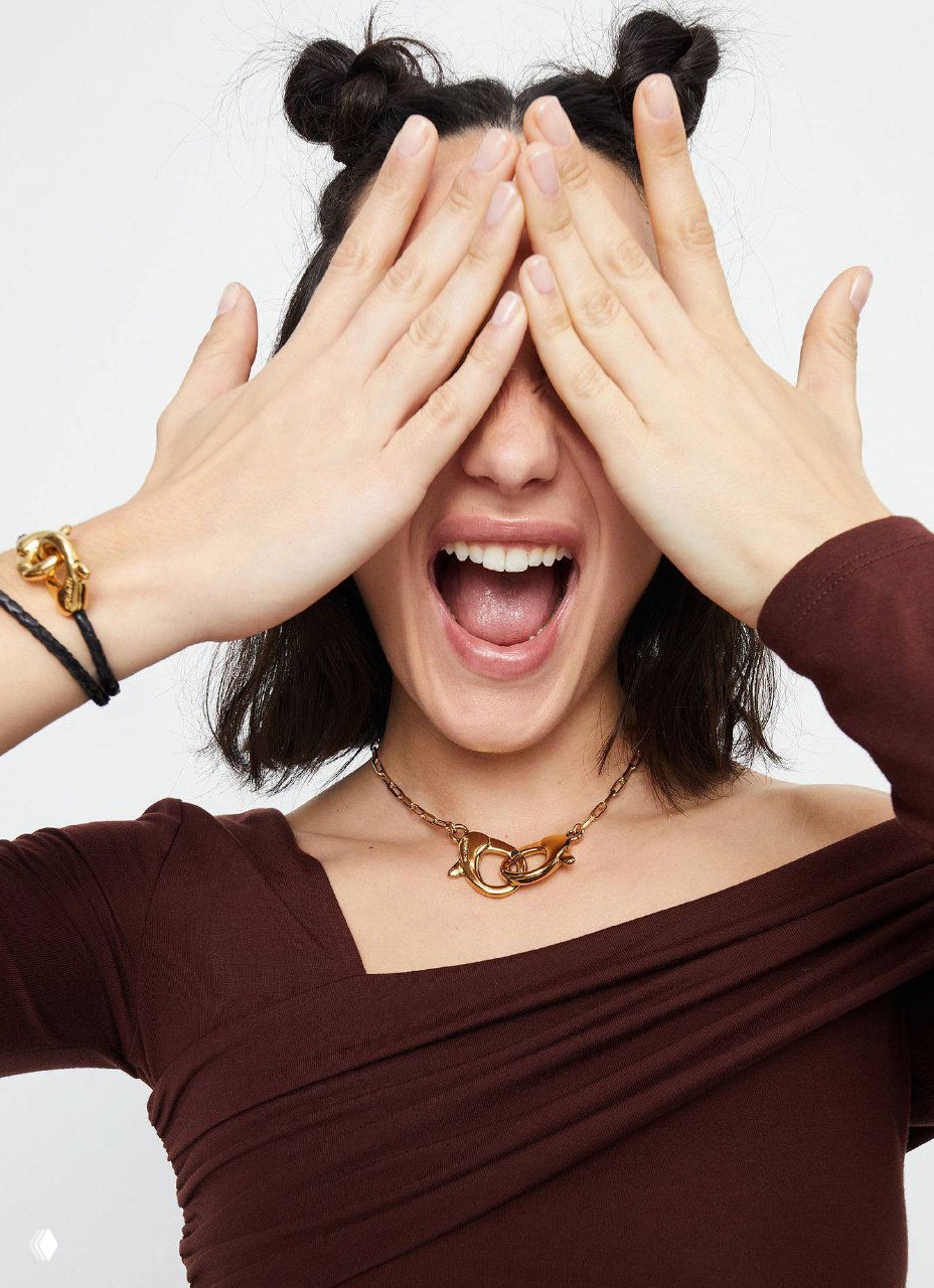 Модель в украшениях UNOde50: ожерелье и браслет с крупными карабинами, естественная эмоция и репрезентация коллекции Ser Inseparable в образе.