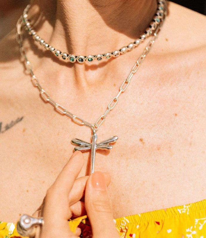 Крупный план кулона в форме стрекозы и тонких цепочек UNOde50 — акцент на дизайне подвески и деталях соединений.