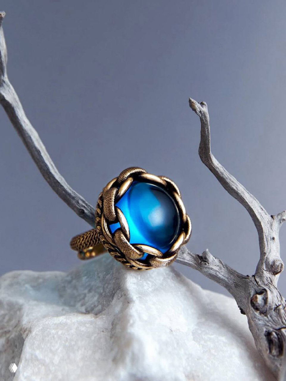 Кольцо из коллекции CATENE с ярким морским синем кабошоном в декоративной бронзовой оправе, предметная съемка на натуральных фактурах.
