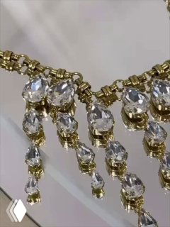 Крупный план украшения Claudio Canzian: многослойная золотая цепочка с подвесками и крупными прозрачными кристаллами, блеск и детализация оправы.