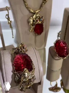 Кольца и серьги с крупными красными камнями на подставках в витрине — насыщенный рубиновый оттенок в золотых деталях от Claudio Canzian.