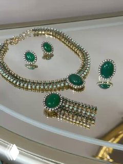 Набор украшений с зелёными вставками: ожерелье, серьги и браслет на витрине — изумрудный тон в сочетании с маленькими дорожками кристаллов.