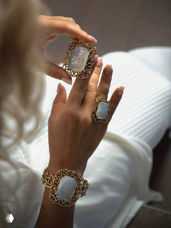 Руки модели с несколькими кольцами и браслетами Claudio Canzian: крупные светлые вставки в массивных золотых рамках, образ для вечернего выхода.