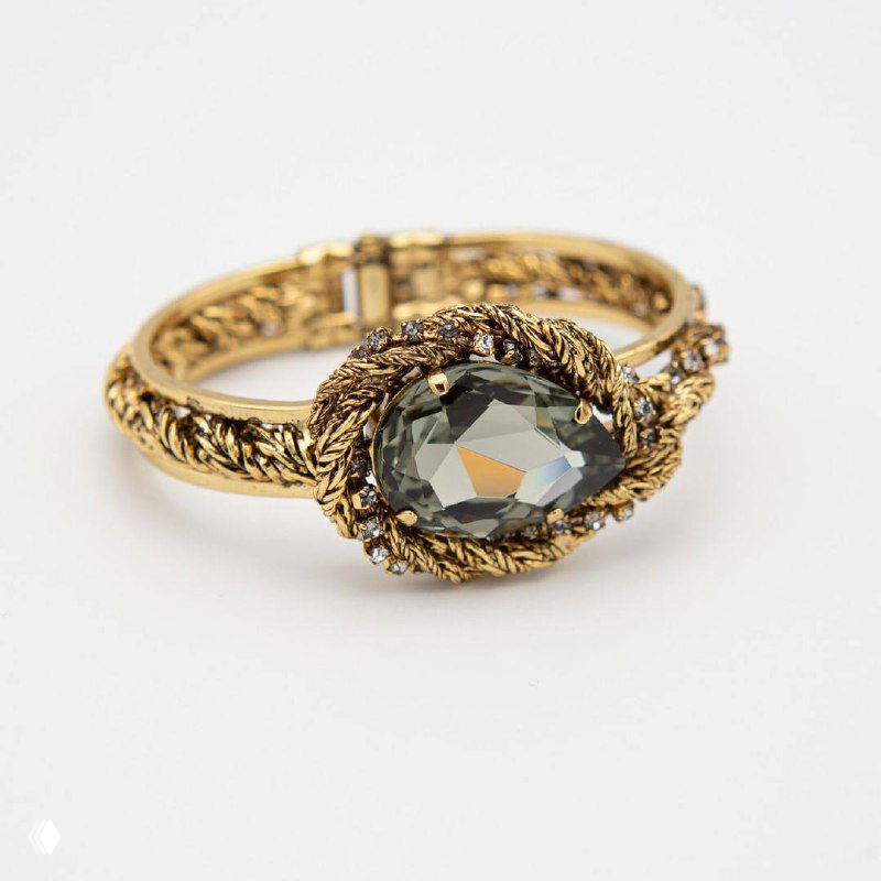 Крупный план кольца Claudio Canzian: витая золотая оправа и крупный серый кристалл на светлом нейтральном фоне, студийная фотосъемка.