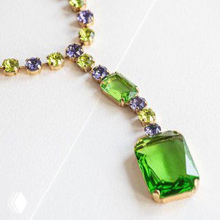 Ожерелье Claudio Canzian с зелеными и фиолетовыми кристаллами: крупный зеленый центральный камень и мелкие цветные вставки на светлом фоне.