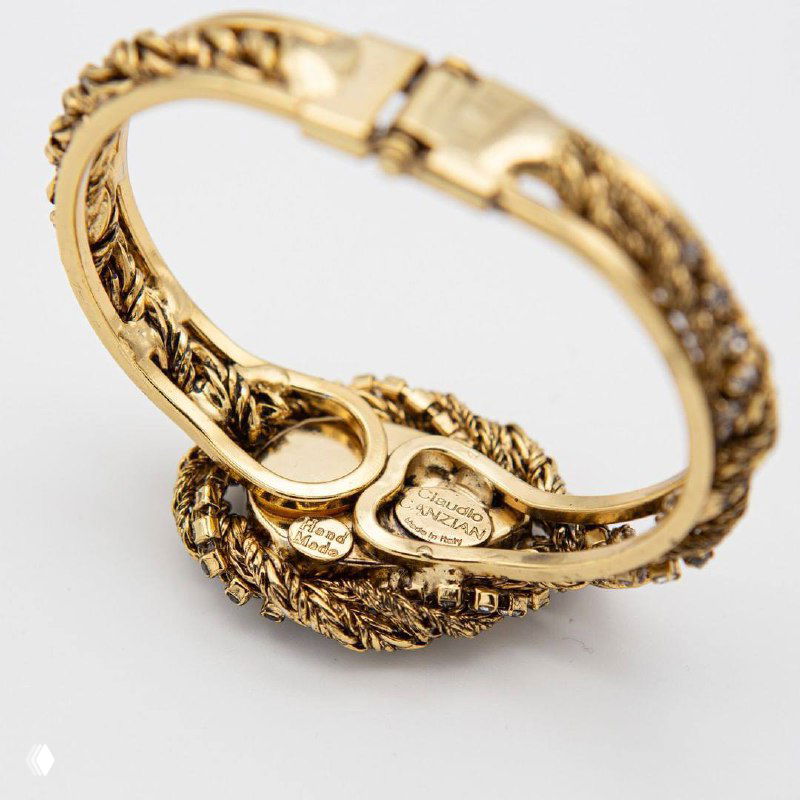 Вид снизу на браслет Claudio Canzian с клеймом или фирменной маркировкой, показана застежка и текстура латуни с позолотой на светлом фоне.