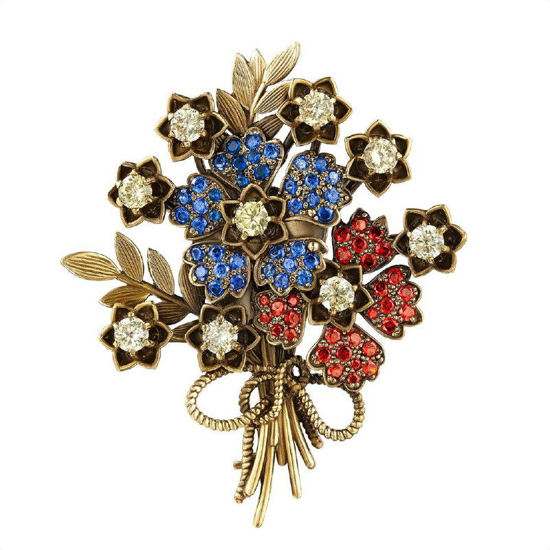 Брошь в виде букета цветов с синими и красными кристаллами на золотистой основе, детальное фото изделия на белом фоне для каталога.