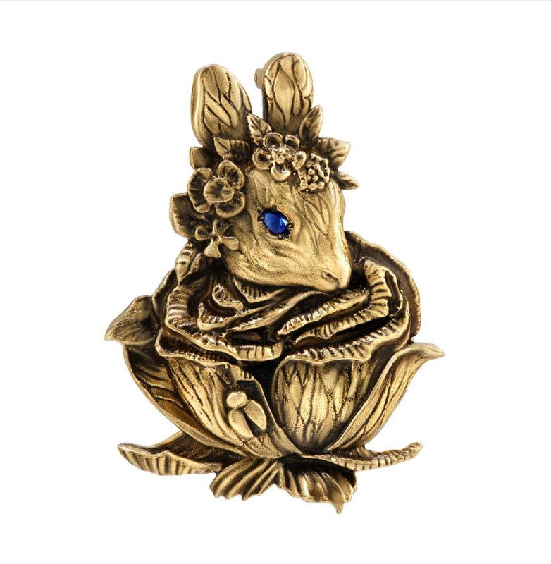 Декоративная бронзовая брошка с изображением зайца в цветке, крупный план изделия на нейтральном фоне для демонстрации художественной отделки.