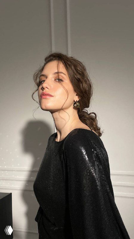 Крупный анфас модели, мягкий боковой свет, серьги и ожерелье подчёркивают праздничный образ и текстуру ткани платья.