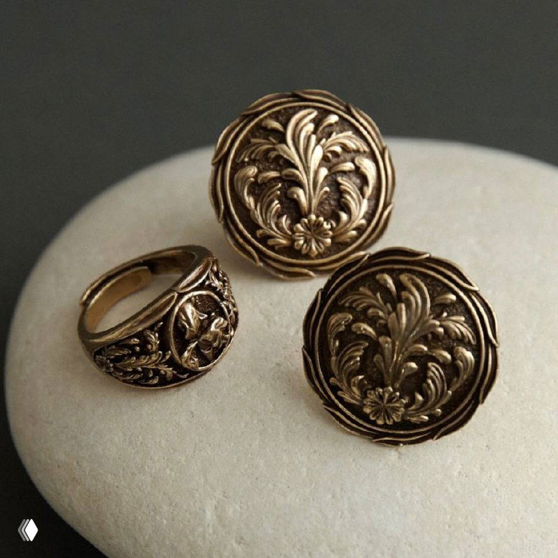 Крупные круглые бронзовые пуговицы или украшения в ретро-стиле с растительным орнаментом, разложенные на светлом фоне — винтажный дизайн.