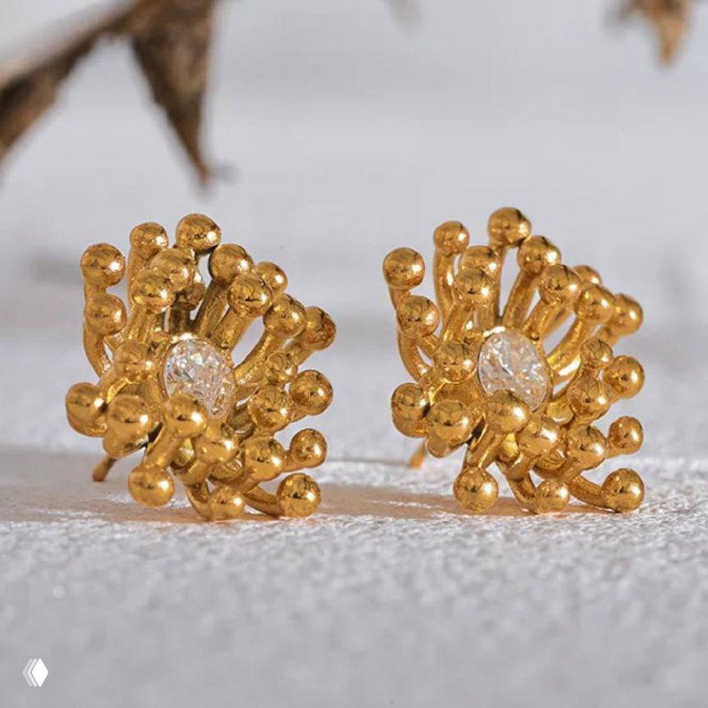 Золотистые серьги с фактурной формой и небольшими бриллиантоподобными вставками на светлом подставке — изящные повседневные серьги.