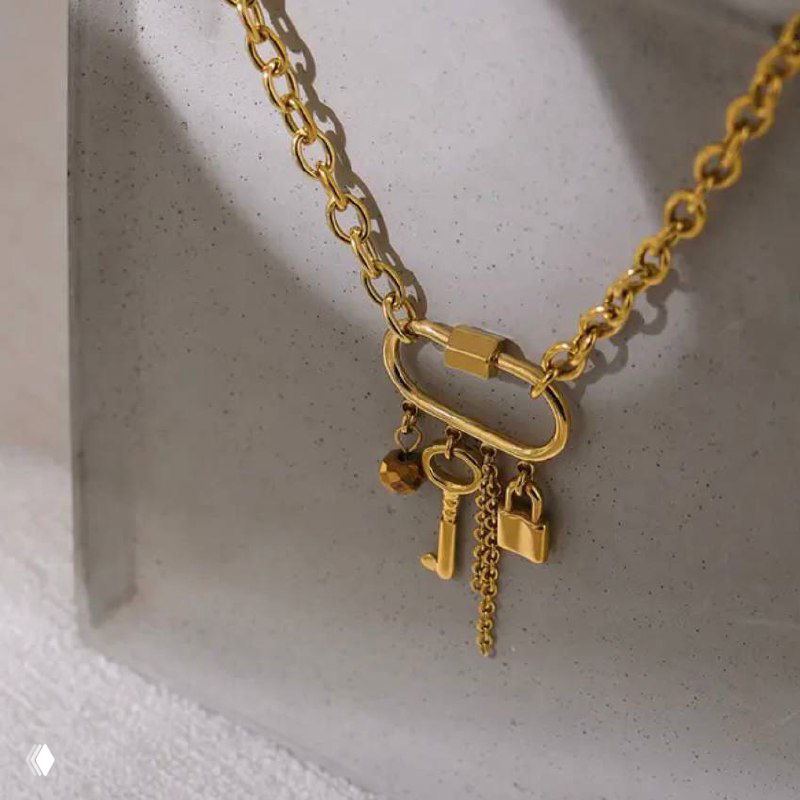 Тонкая золотая цепочка с подвесками в виде миниатюрных ключиков и символов, на светлом фоне — трендовые малые подвески для повседневного ношения.
