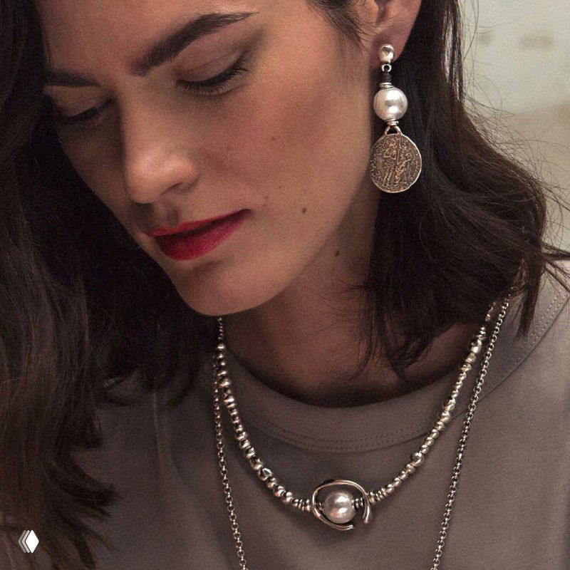 Портрет женщины в серьгах и двухслойном серебряном ожерелье UNOde50, натуральный макияж и стилизованный образ для демонстрации аксессуаров в каталоге