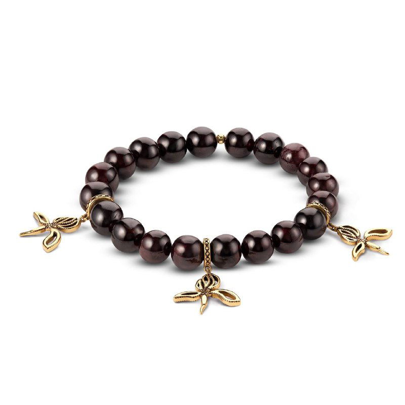 Браслет из гладких гранатовых бусин с золотистыми подвесками‑листиками, крупный план украшения из коллекции TONDA на белом фоне.