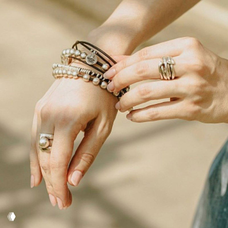 Несколько браслетов и кольцо в стиле UNOde50 на женском запястье — образ с комбинированной текстурой кожи и металла.