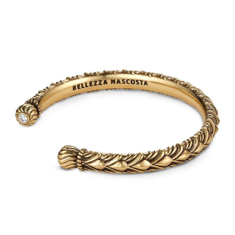 Крупный план золотистого манжета‑браслета в винтажном стиле: рельефный узор по всей поверхности и видна гравировка на внутренней стороне.