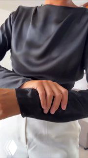 Крупный план рук модели в серой блузе и белых брюках, демонстрация запястья и украшения в стиле Coeur de Lion.