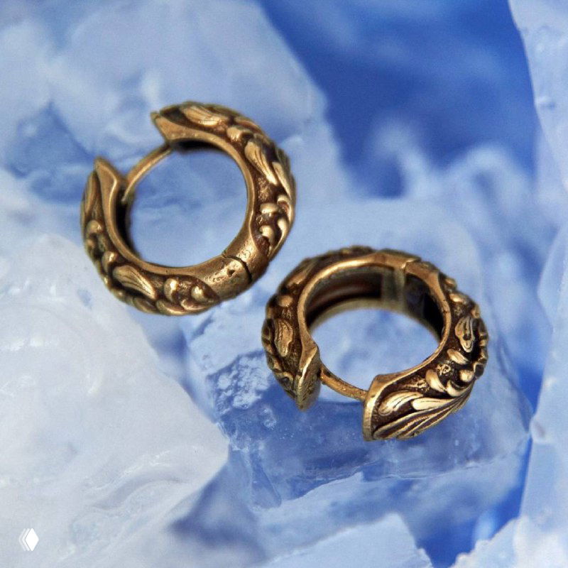 Крупный план золотистых круглых серьг-колец Fiore di Firenze на светло-голубом фоне, демонстрация фактуры металла и декоративных деталей для летнего образа