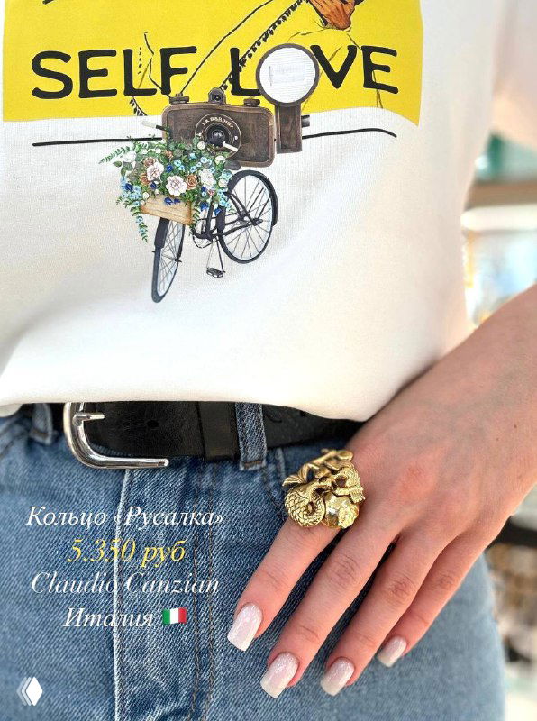 Крупный план руки с акцентным коктейльным кольцом в виде русалки от Claudio Canzian; показан стильный маникюр.