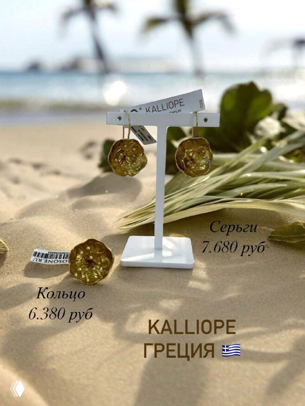 Серьги и кольцо бренда KALLIOPE на песчаном берегу; композиция передаёт морскую атмосферу и летний контекст коллекции.