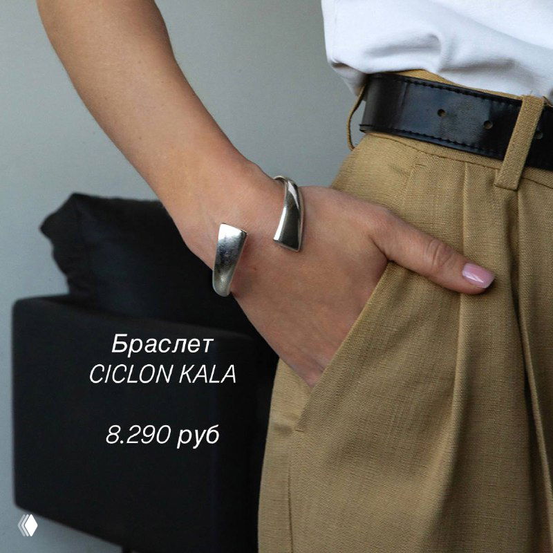 Рука в кармане брюк демонстрирует открытый серебристый браслет Ciclon KALA на тоне одежды, подчёркивая летний образ и фактуру металла.