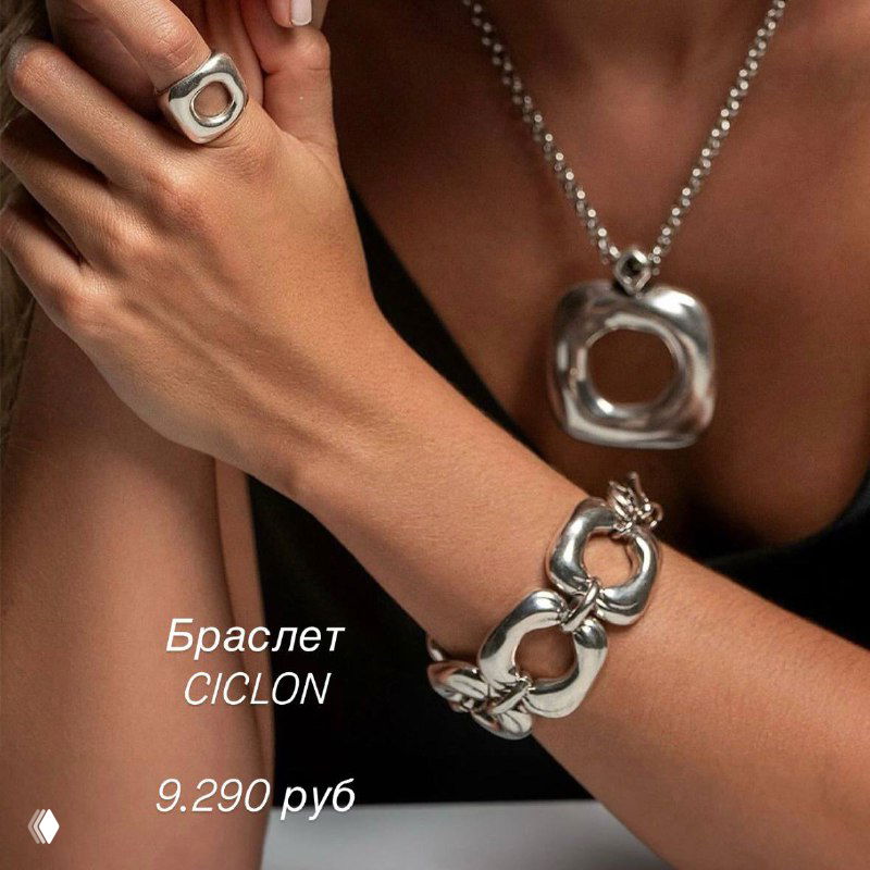 Рекламный кадр модели в темном наряде с комплектом серебристых украшений Ciclon: браслет и подвеска крупным планом, показана фактура металла.
