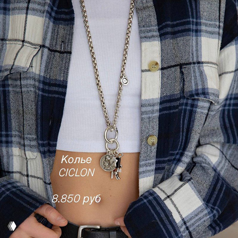 Крупный план образа с длинной цепочкой и кулоном Ciclon на модели в клетчатой рубашке, показаны пропорции подвески и стиль ношения.