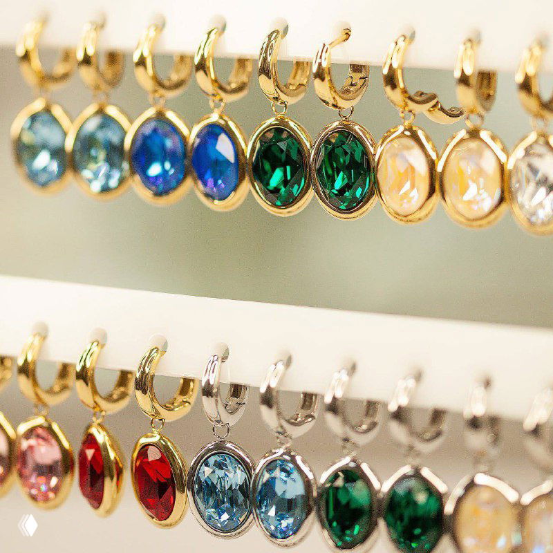 Подвески и серьги QUDO на стойке: разноцветные овальные кристаллы — синий, зелёный, бежевый — в золотой и родиевой оправе