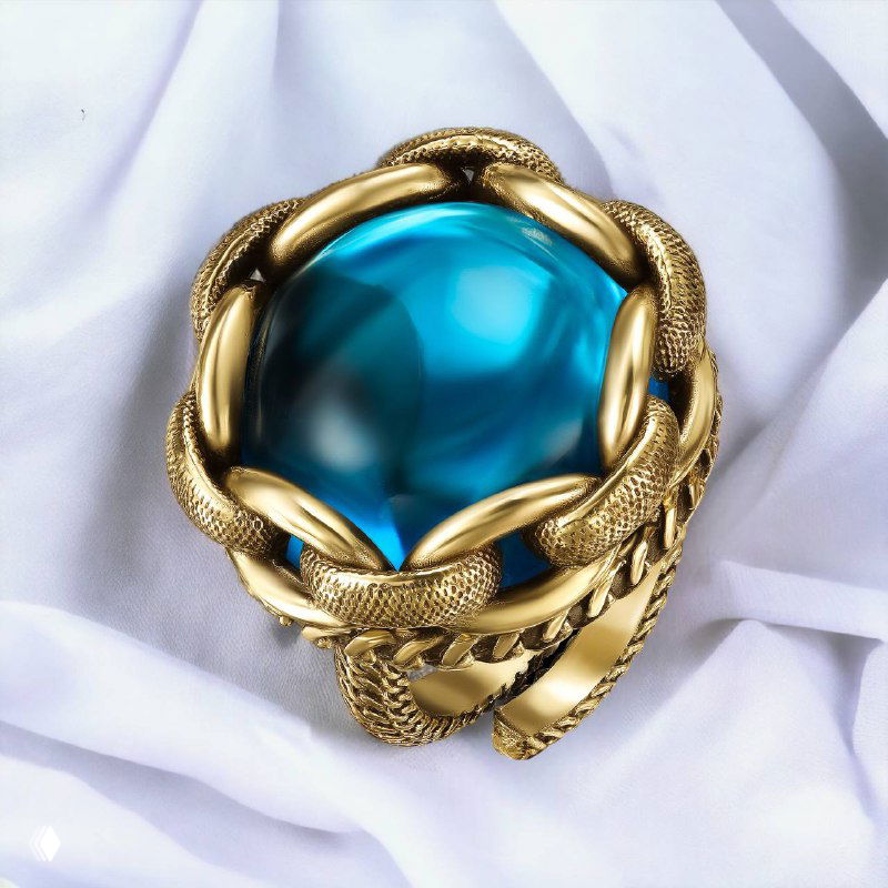 Крупный план коктейльного кольца Fiore di Firenze: насыщенно-голубой крупный алпанит в золотистом плетёном обрамлении, украшение лежит на светлой ткани.