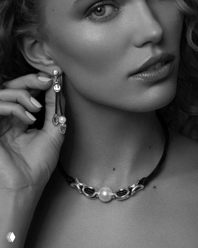 Чёрно-белая фотография модели в портрете, показывающая кожаное колье Legend с центральной жемчужиной и длинными серьгами.