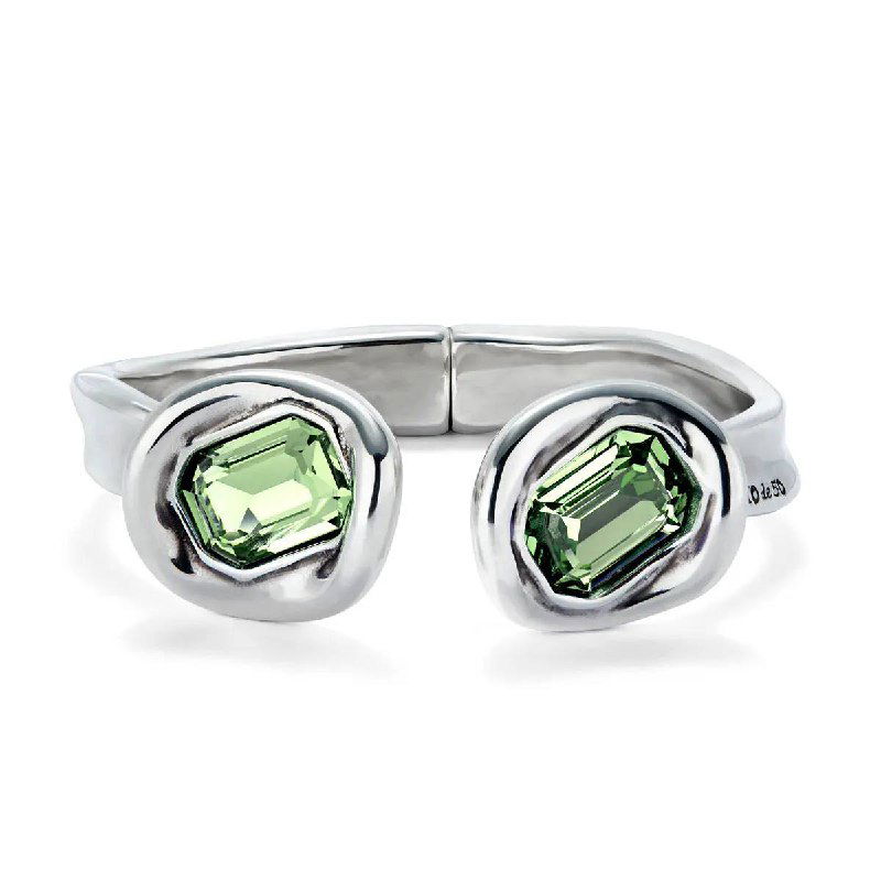 Крупный план серебристого браслета UNOde50 с парой светло‑зеленых кристаллов на белом фоне, демонстрация деталей и цветовой гаммы коллекции.