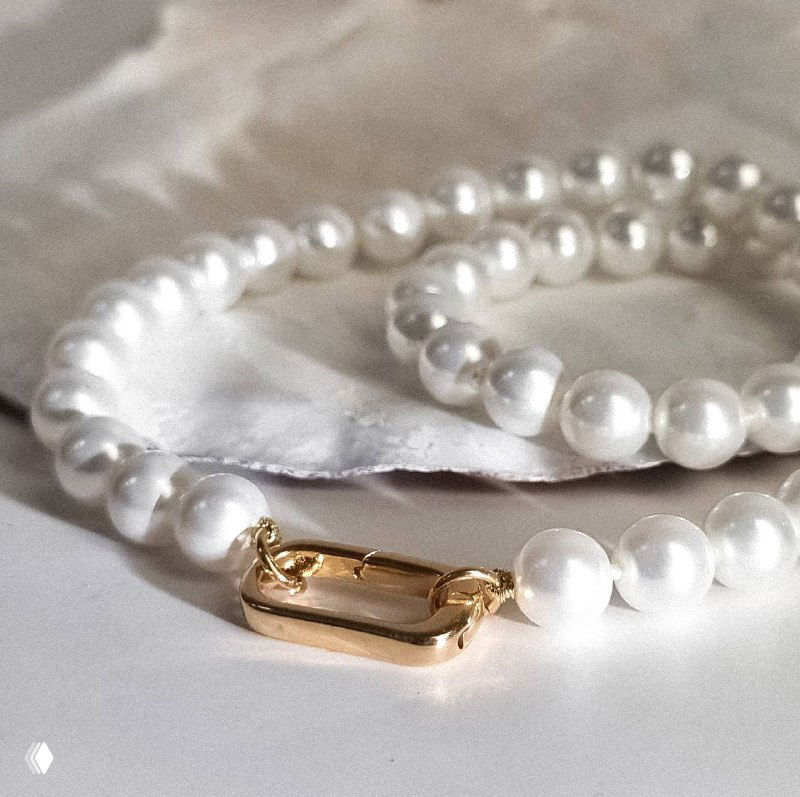 Крупный план жемчужного ожерелья Майорка с золотым замком на светлом фоне — демонстрация качества покрытия Madreperla.