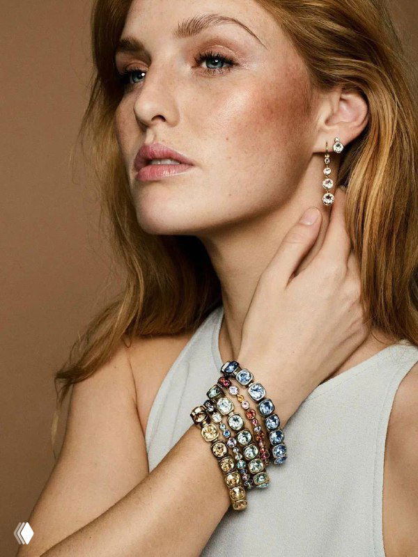 Модель демонстрирует несколько широких браслетов CONIAN с крупными кристаллами Swarovski на запястье в студийной рекламной съёмке