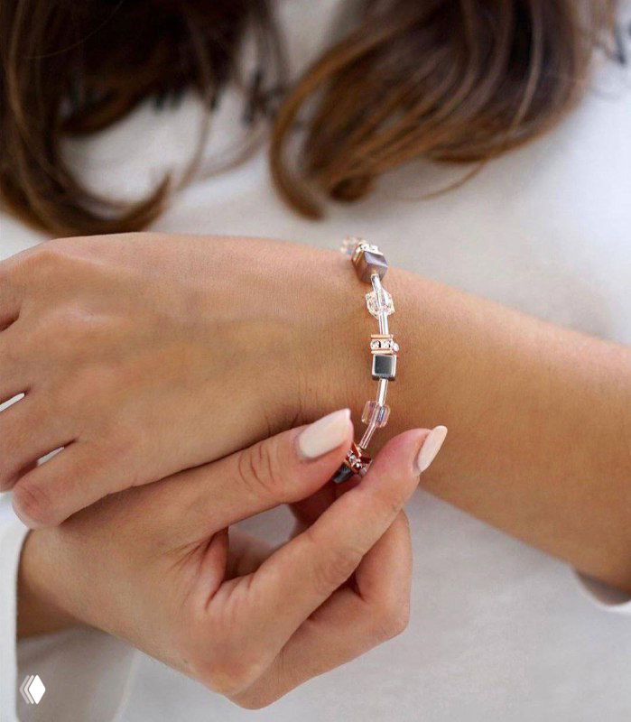 Крупный план женской руки с браслетом Coeur de Lion: сочетание серебристых, розовых и прозрачных кубиков, демонстрация застёжки и посадки на запястье.